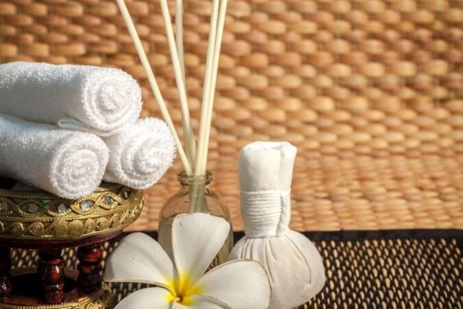 Des serviettes roulées et une fleur de frangipanier composent une ambiance spa relaxante.