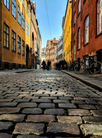 Rue pavée bordée de bâtiments colorés lors d'une découverte de Copenhague quartier par quartier.